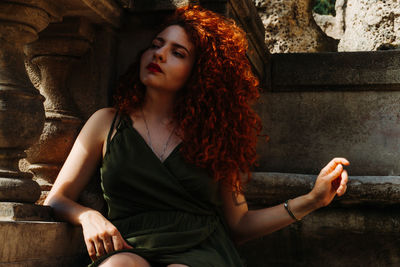 Young woman looking down while sitting outdoors