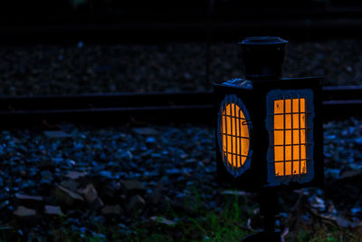 Illuminated railroad tracks on field at night