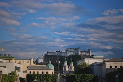 Buildings in city against cloudy sky