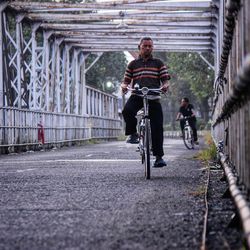 Men riding bicycle on bridge in city