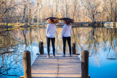 Women standing by lake against trees