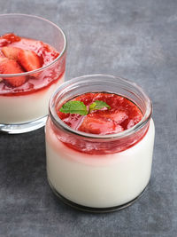 Sweet vanilla silky pudding dessert with strawberry sauce, sliced fresh strawberries and mint 