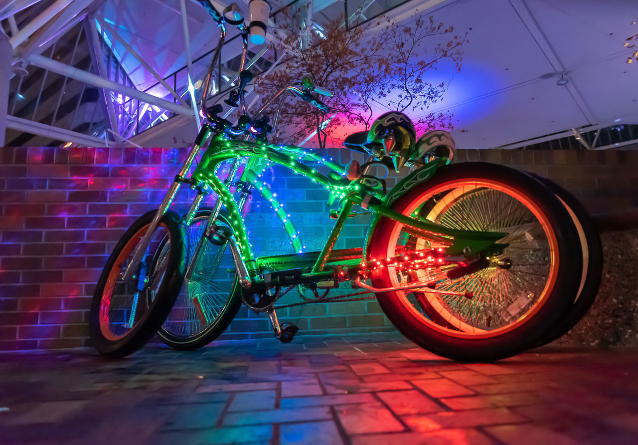 BICYCLES PARKED ON ILLUMINATED WALL