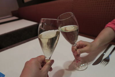 Midsection of woman holding wine glass on table