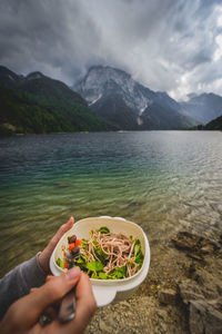 Man holding food in mountains against sky