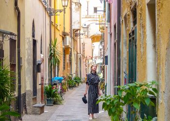 Woman standing on alley amidst buildings