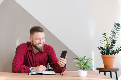 Successful relaxed red shirted freelancer discussing over video communication