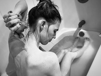 A woman in a bathtub washing her back