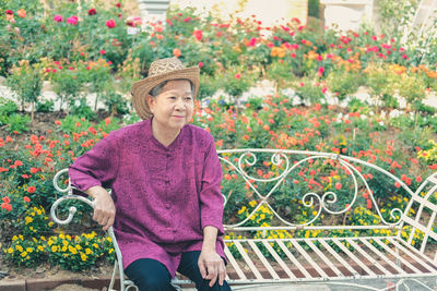 Smiling senior woman wearing hat looking away while sitting outdoors