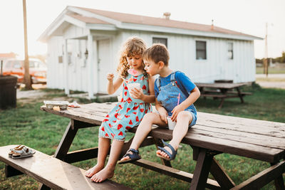 Young brother looking at sister's snowcone outside in summer