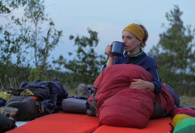 Woman drinking against sky during sunset