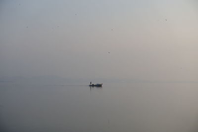 Silhouette boat sailing on sea against clear sky during sunset