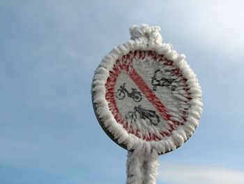 Low angle view of frosted road sign against sky