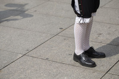 Low section of woman standing on footpath