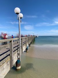 Pier on beach against sky