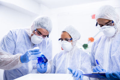 Scientists examining chemical in flask at laboratory