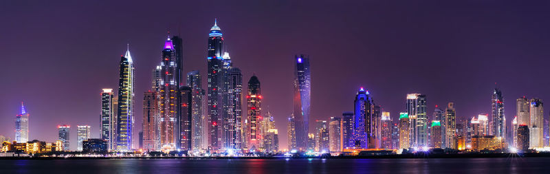 Illuminated modern buildings against sky at night