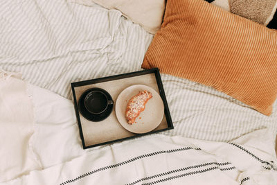 Breakfast in bed a cup of coffee and a delicious croissant on a plate on a tray in a cozy house