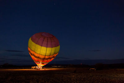 Hot air balloon on field against sky at night