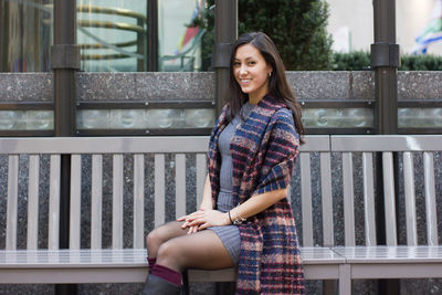 Portrait of happy beautiful woman with scarf sitting on bench