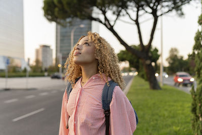 Thoughtful blond woman with backpack on street