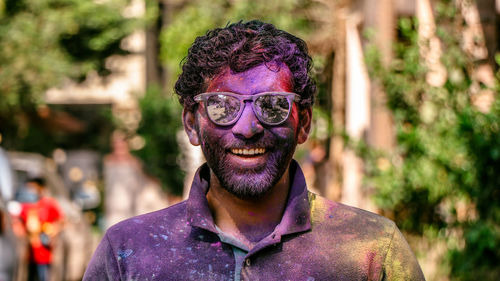 Portrait of smiling man wearing sunglasses during holi