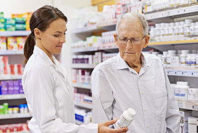 Pharmacist assisting senior customer at store