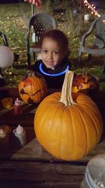 Portrait of cute girl lying on pumpkin at night