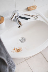 High angle view of faucet and sink in bathroom at home with slices of hair
