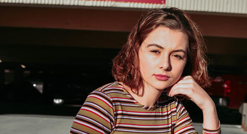 Portrait of beautiful young woman sitting outdoors during sunny day