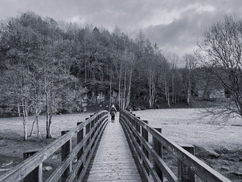 Black and white woman walking across a wooden bridge