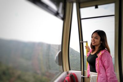 Young woman standing by train window