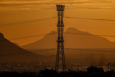 Silhouette electricity pylon against sky during sunset