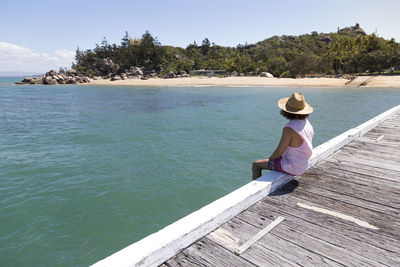 Woman sitting on shore against sea