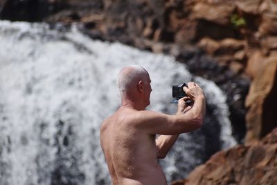 Full length of shirtless man on rock