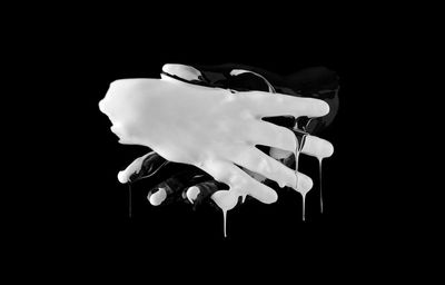 Close-up of hand holding umbrella against black background