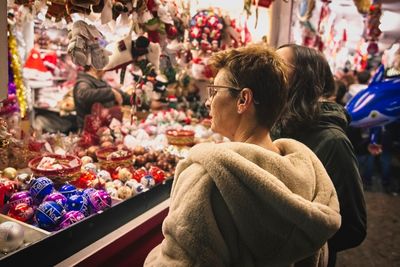 Woman with granddaughter buying decorations during christmas at night