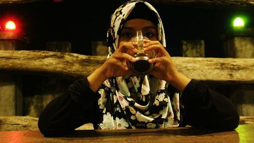 Portrait of woman in hijab having drink at table