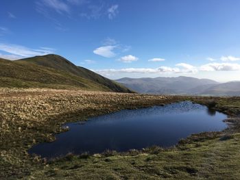 Scenic view of lake and mountains against blue sky