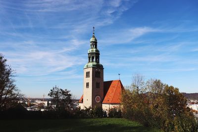 Tower amidst trees and buildings against sky