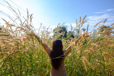 Rear view of woman standing on grass against clear sky