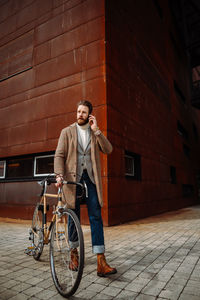 Side view of young man riding bicycle on footpath
