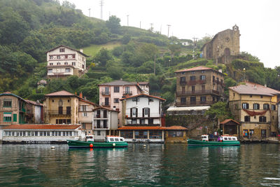 Boats in river by buildings in city