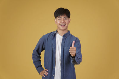 Portrait of smiling man standing against yellow background