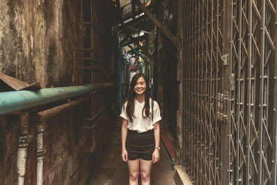 Portrait of young woman standing in alley