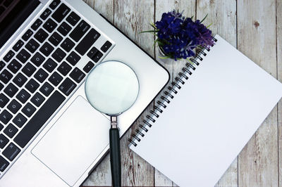 High angle view of laptop with magnifying glass and book on table