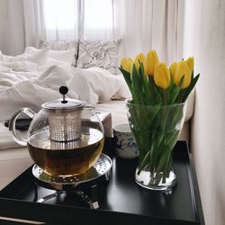 Close-up of tulips in vase by herbal tea kettle on table at home