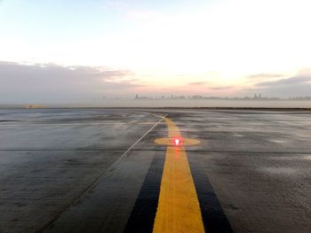 Airplane on road against sky during sunset