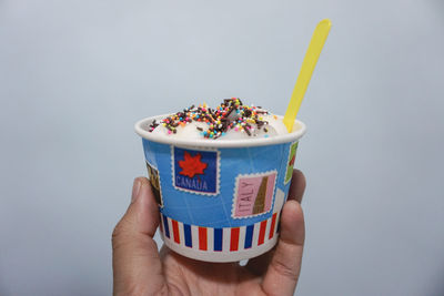 Close-up of hand holding drink against white background