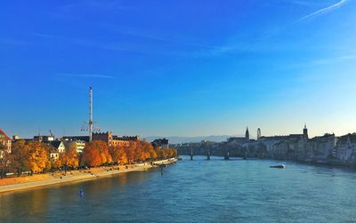 Scenic view of river by city against blue sky